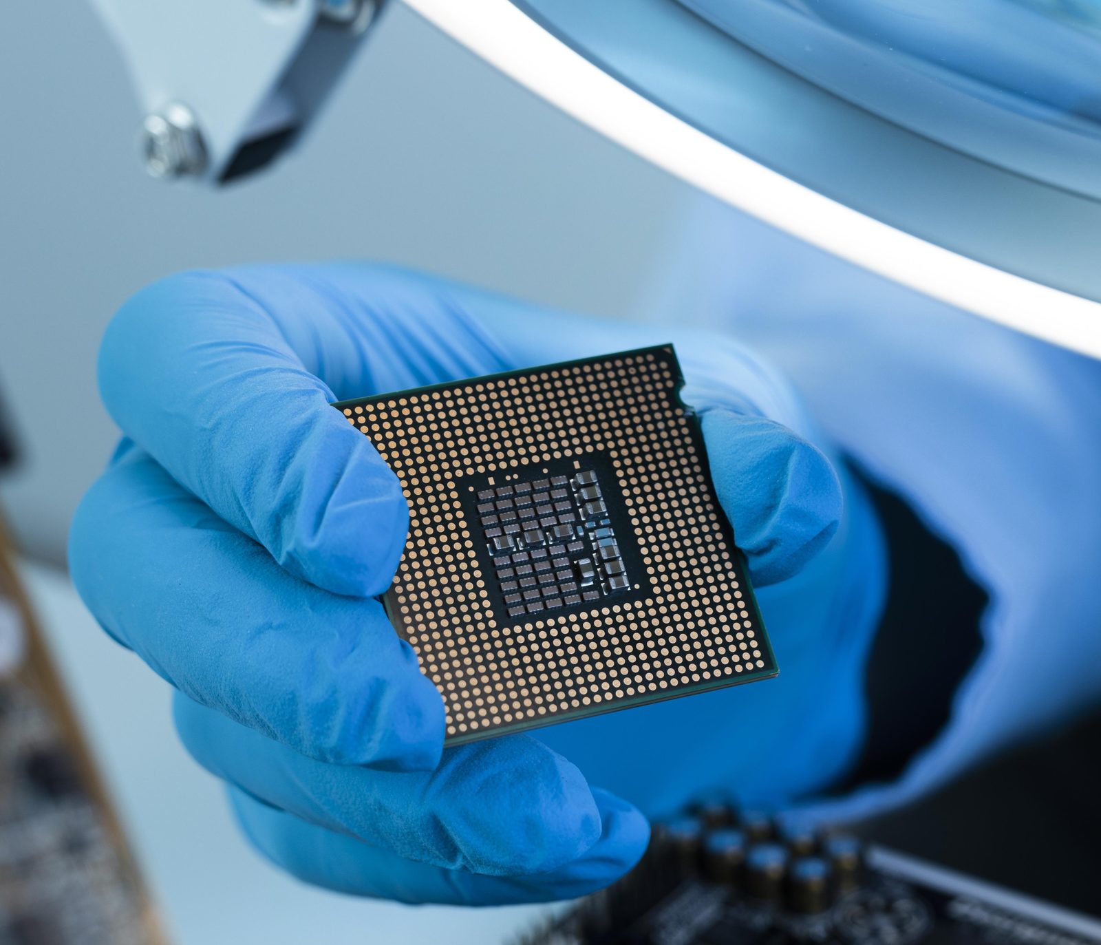 A gloved hand holding a microprocessor in a clean room